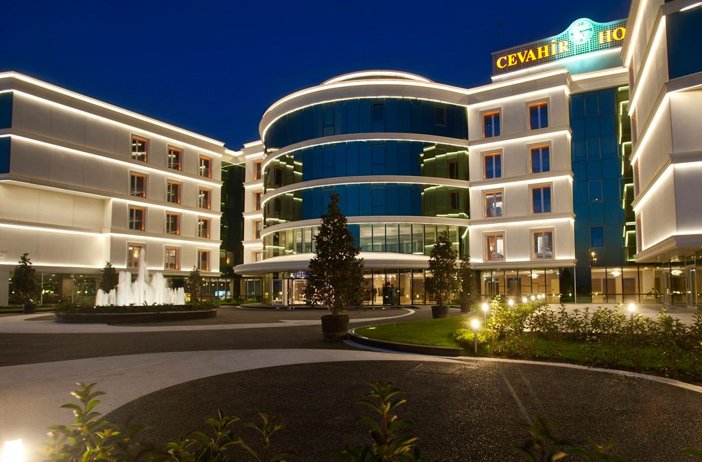 A modern hotel building with illuminated facade and glass windows at dusk.