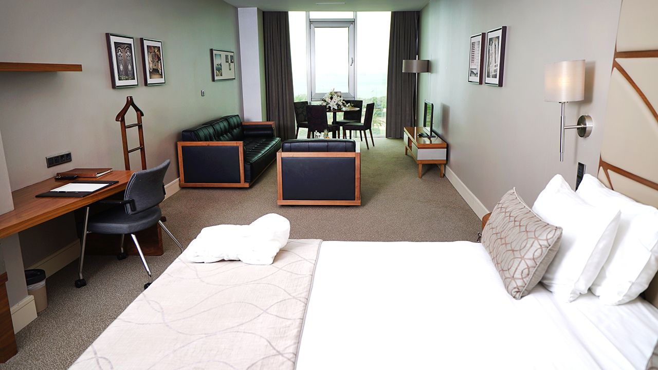 A modern hotel suite featuring a comfortable bed, a living area, and a dining table.