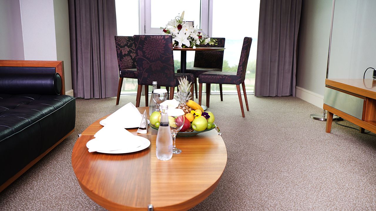 A modern living area featuring a coffee table with fruit and a dining table.