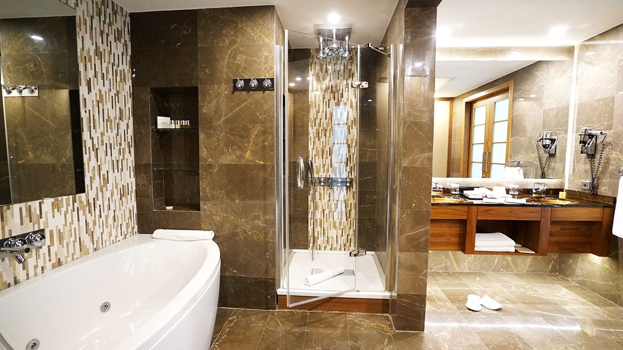 A luxurious bathroom with a white jacuzzi tub, glass shower, and elegant brown marble.