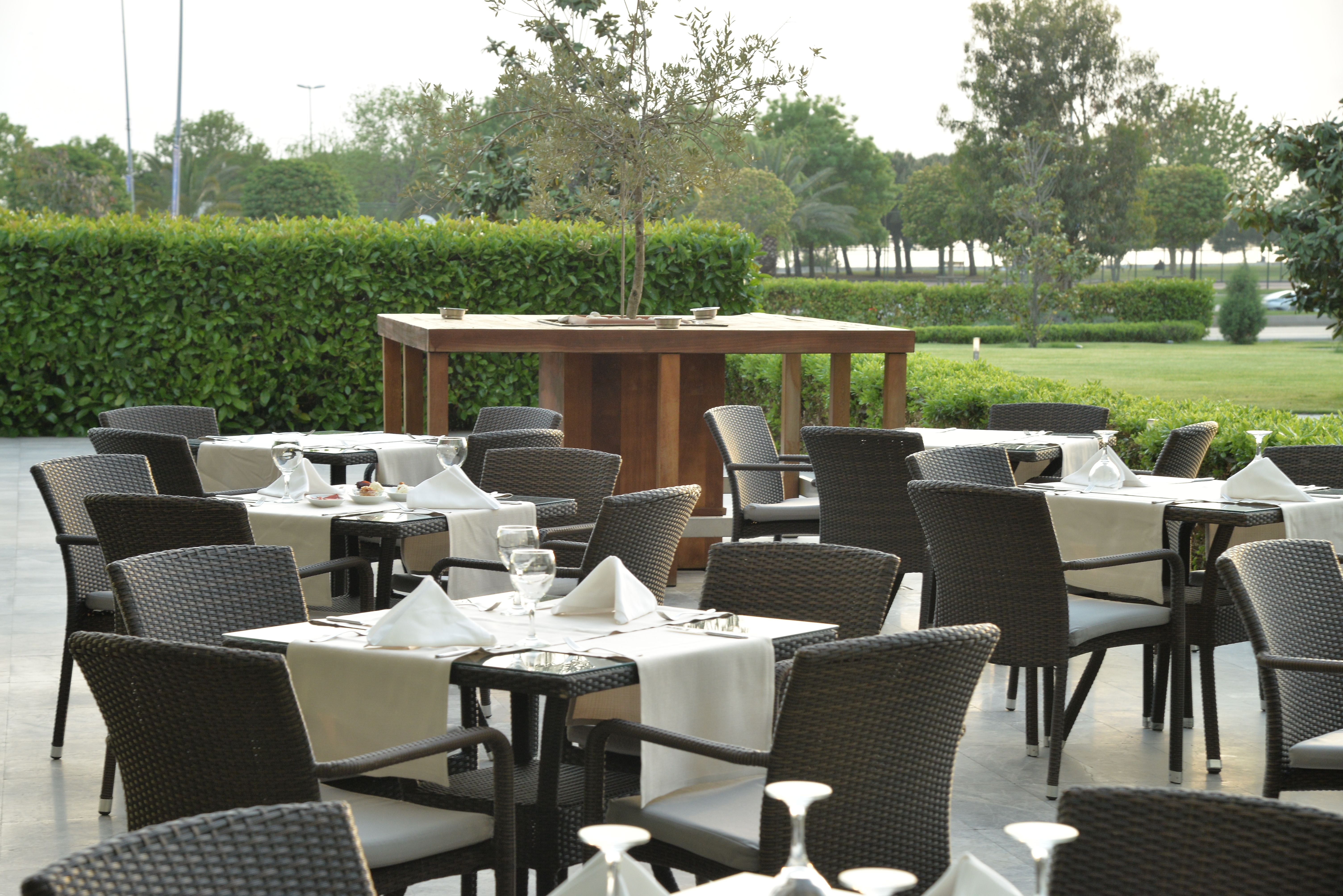 Outdoor dining area with numerous tables set with white linens and chairs.