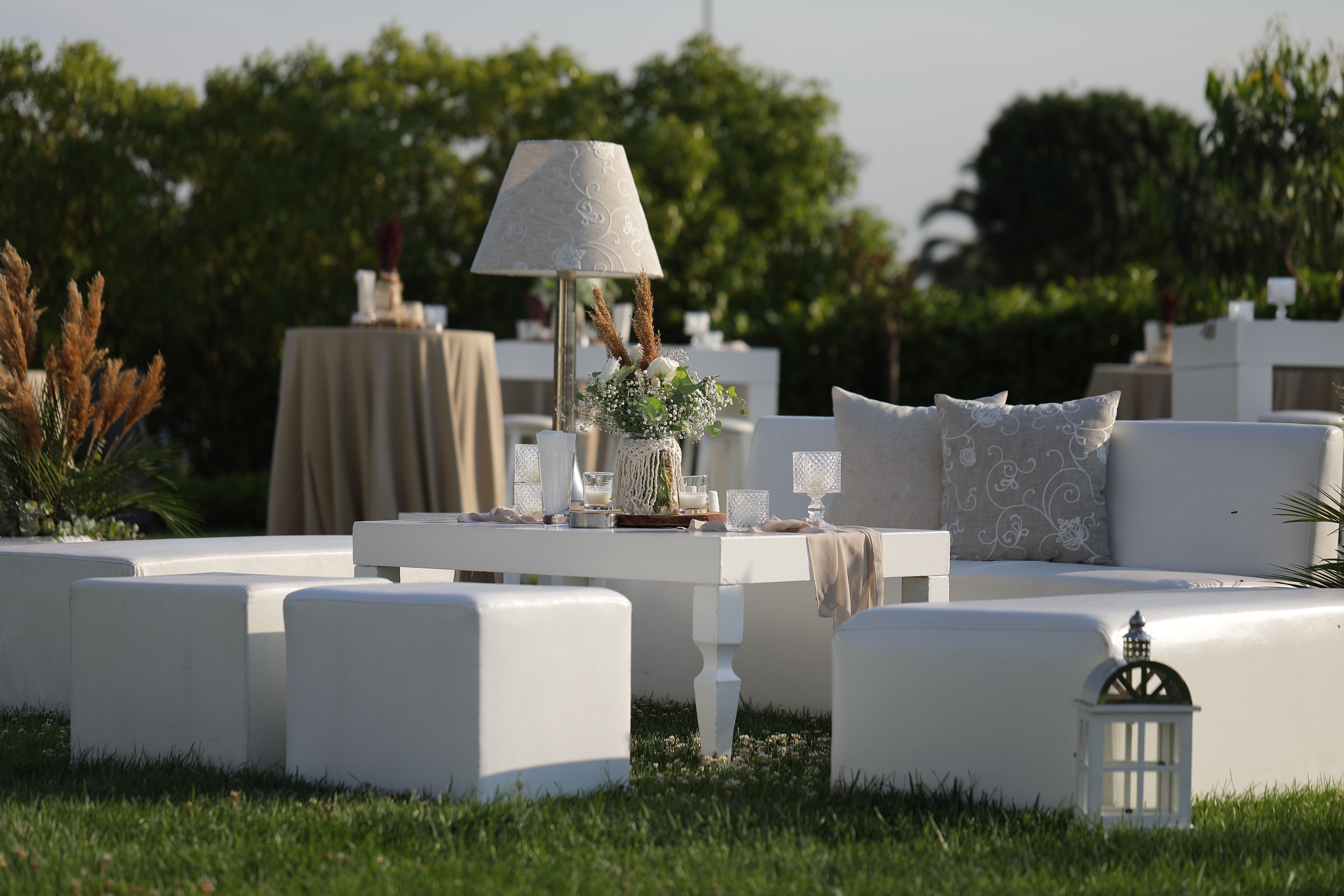 Outdoor lounge area with white modular sofas, ottomans, and a coffee table.