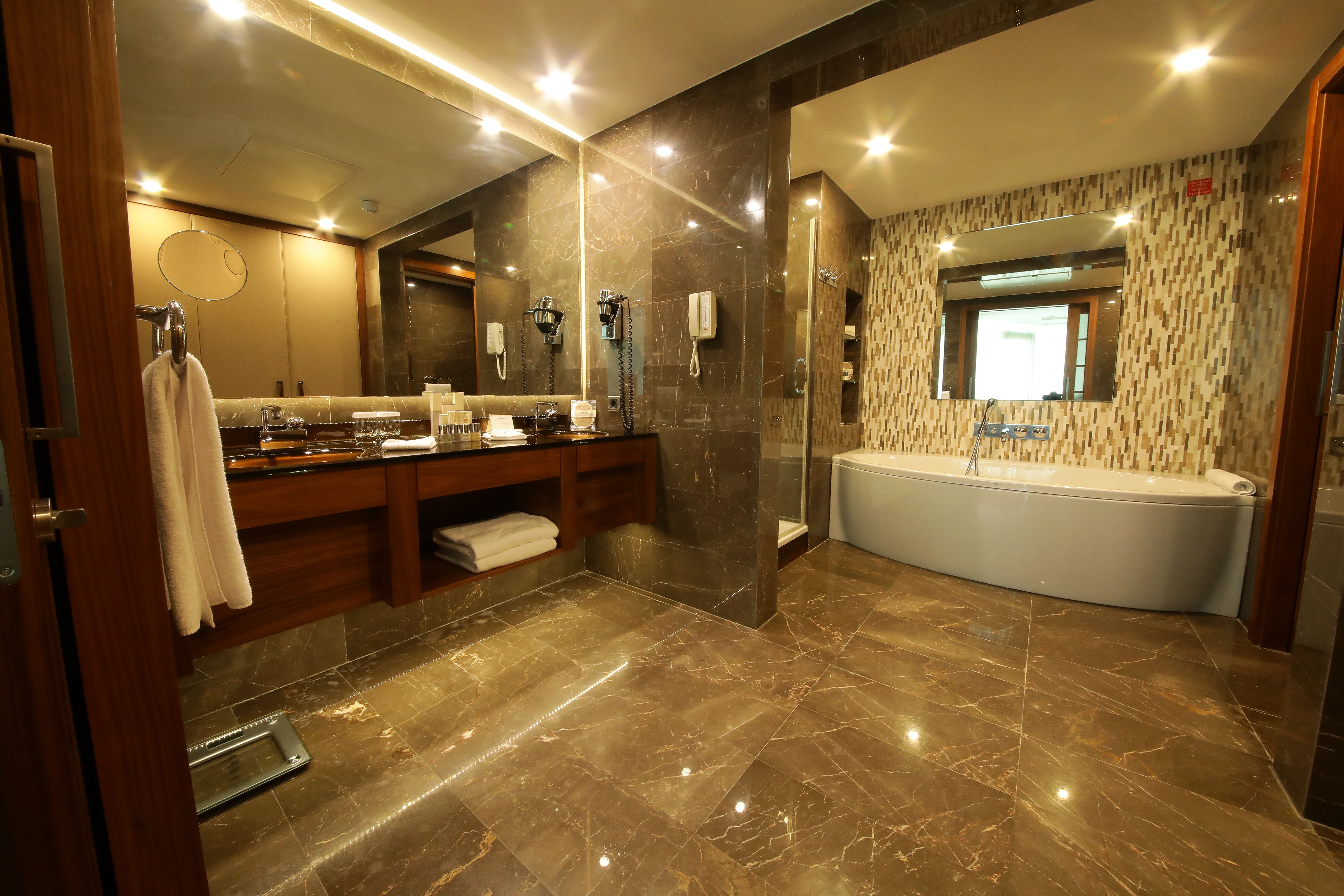 A luxurious bathroom featuring a double vanity, large mirror, and freestanding white bathtub.