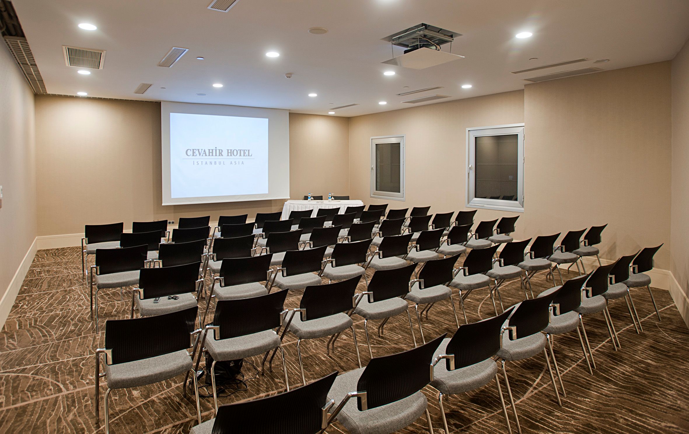 Modern conference room with rows of empty chairs facing a projector screen.
