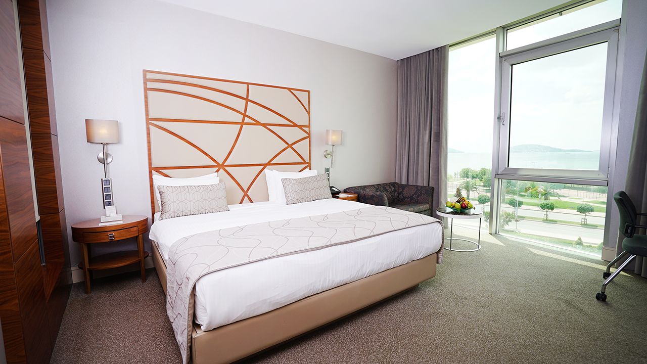 Modern hotel room with a large bed, stylish headboard, and a panoramic window view.