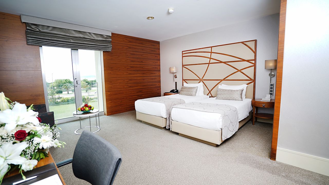 Spacious hotel room with two beds, a large window, and a garden view.