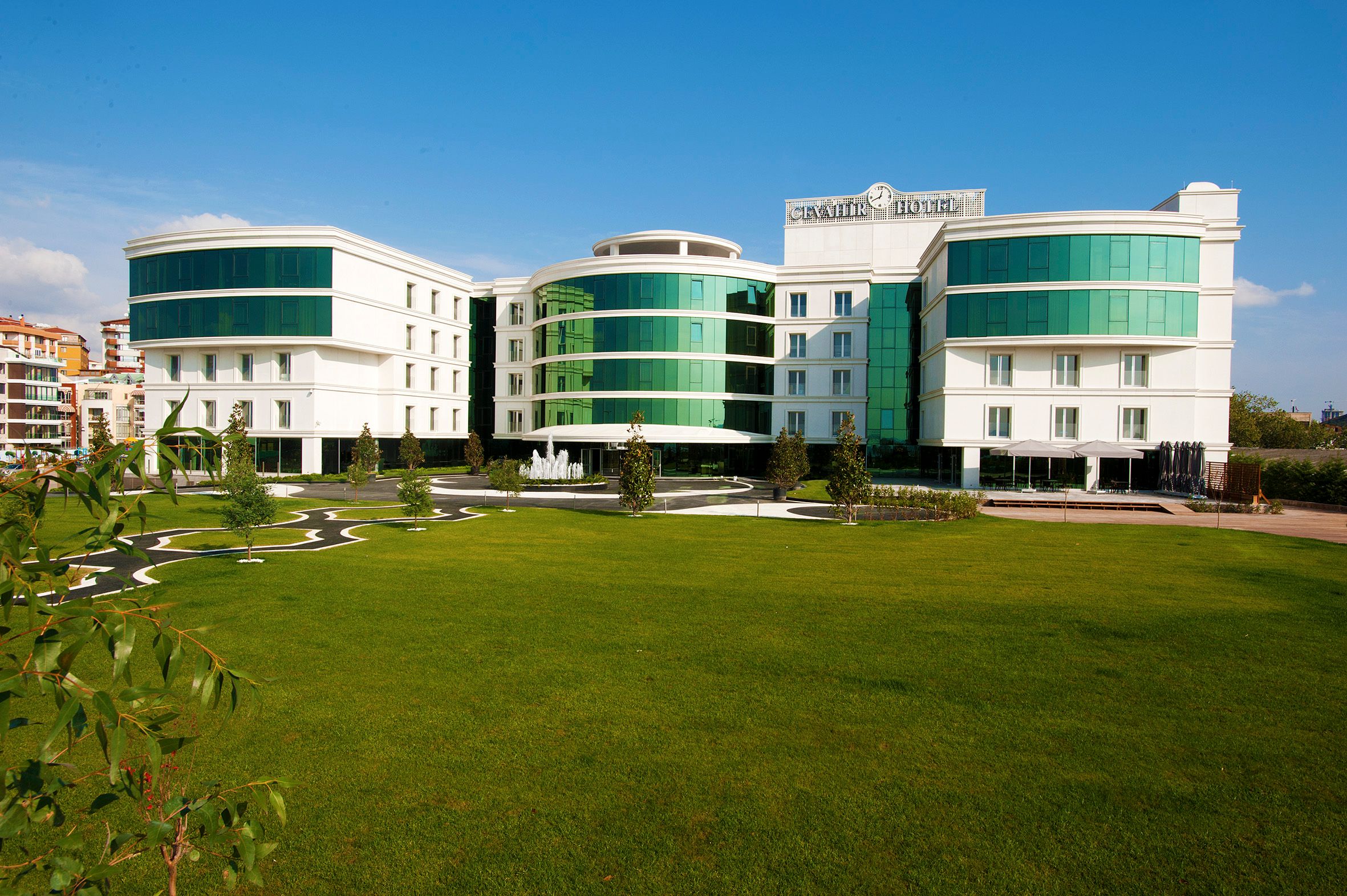 Modern white building with green glass windows and a well-maintained lawn.