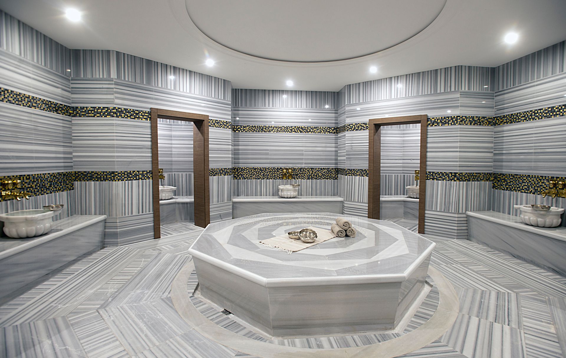 Luxurious Turkish bath with marble walls, a central octagonal heated stone, and two doorways.