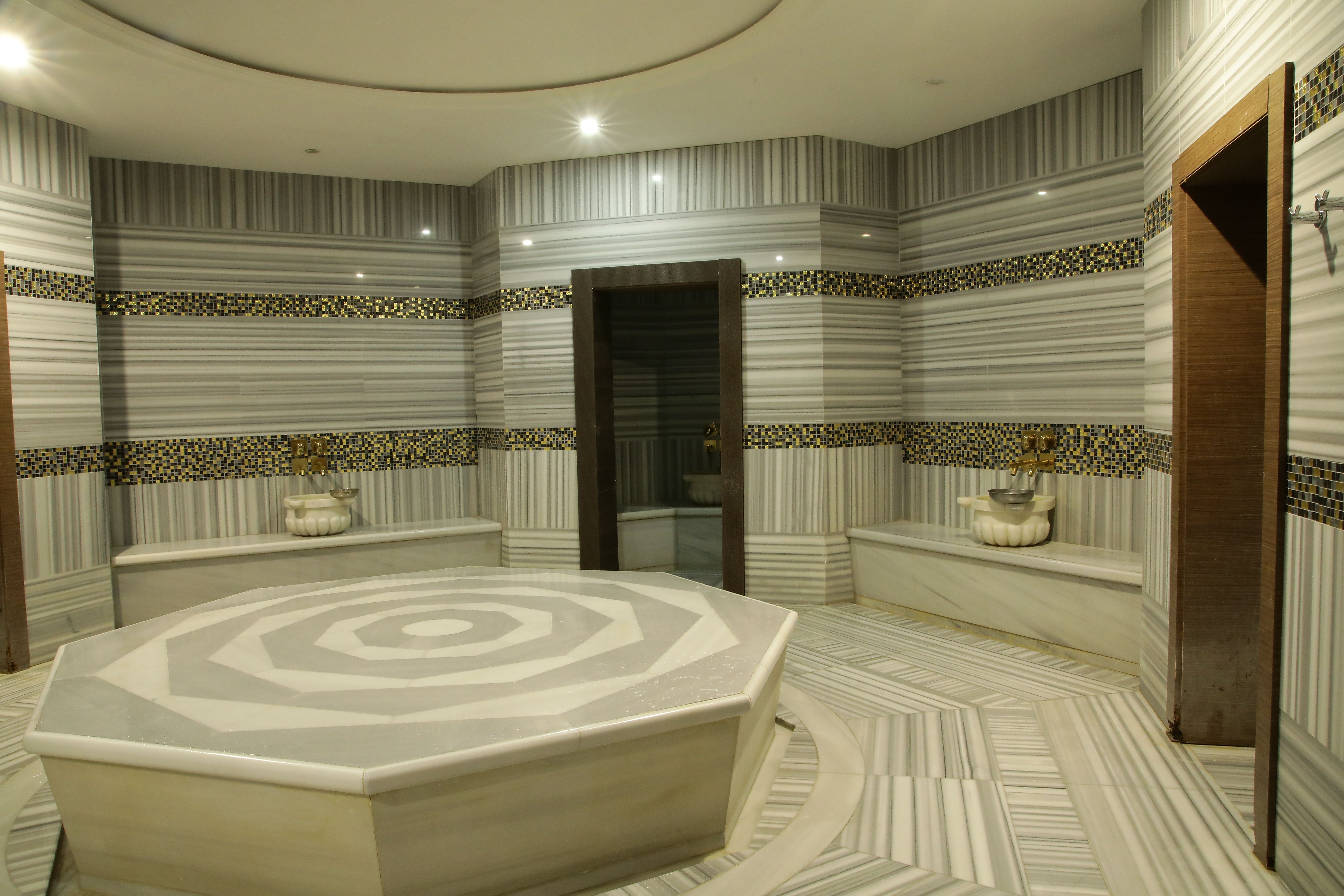 Octagonal marble platform in a steam room with striped marble walls and benches.