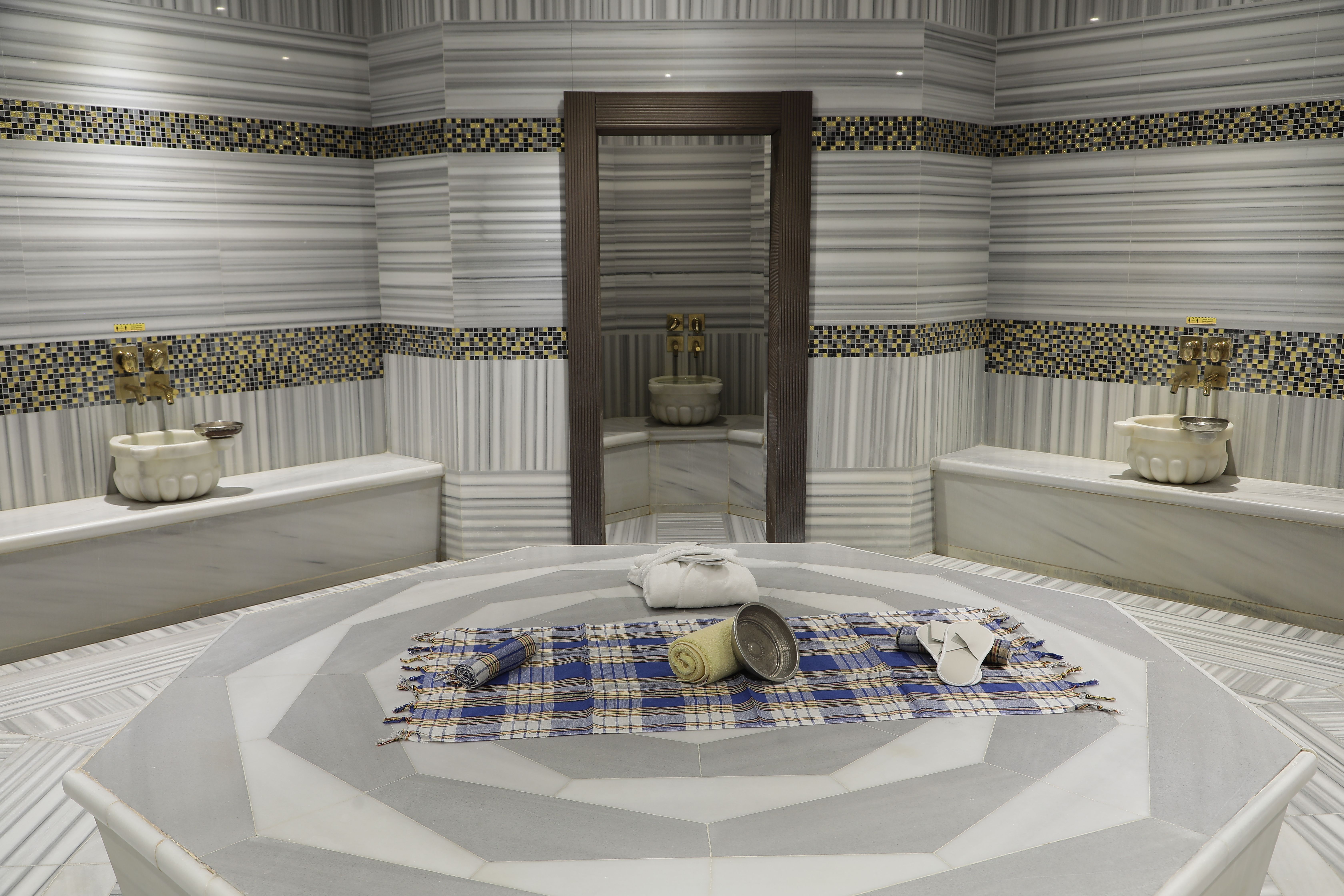 A luxurious Turkish bath with marble benches and a patterned floor.