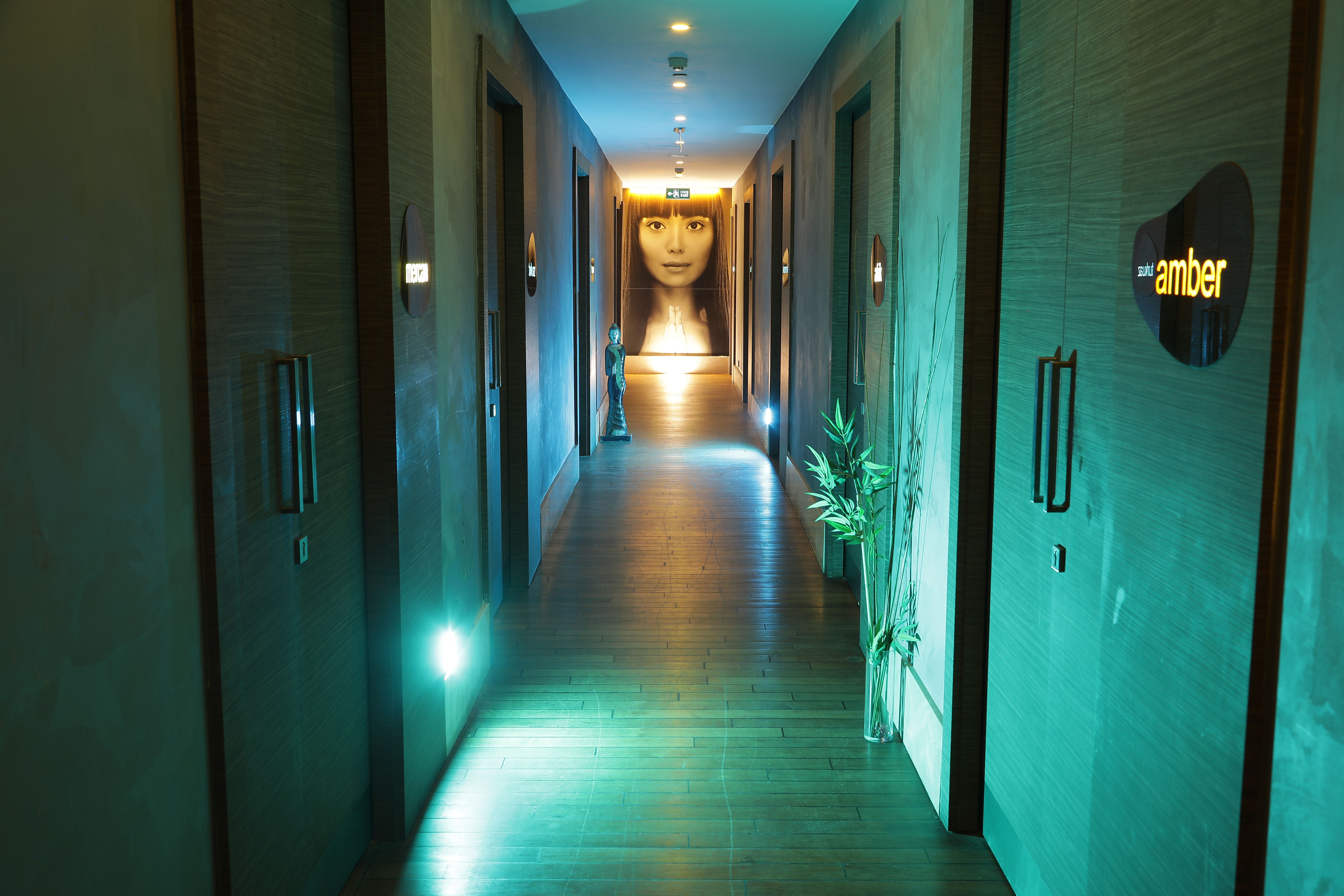 A dimly lit hotel hallway with doors on both sides and a large illuminated face at the far end.