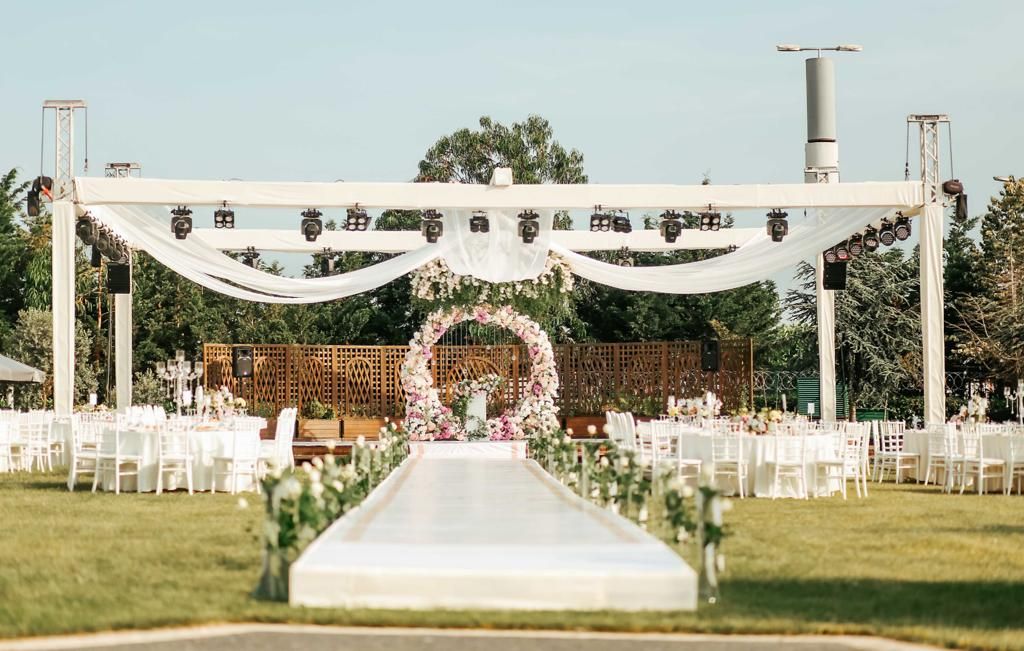 A wedding ceremony setup with white chairs, a floral arch, and a decorated aisle.