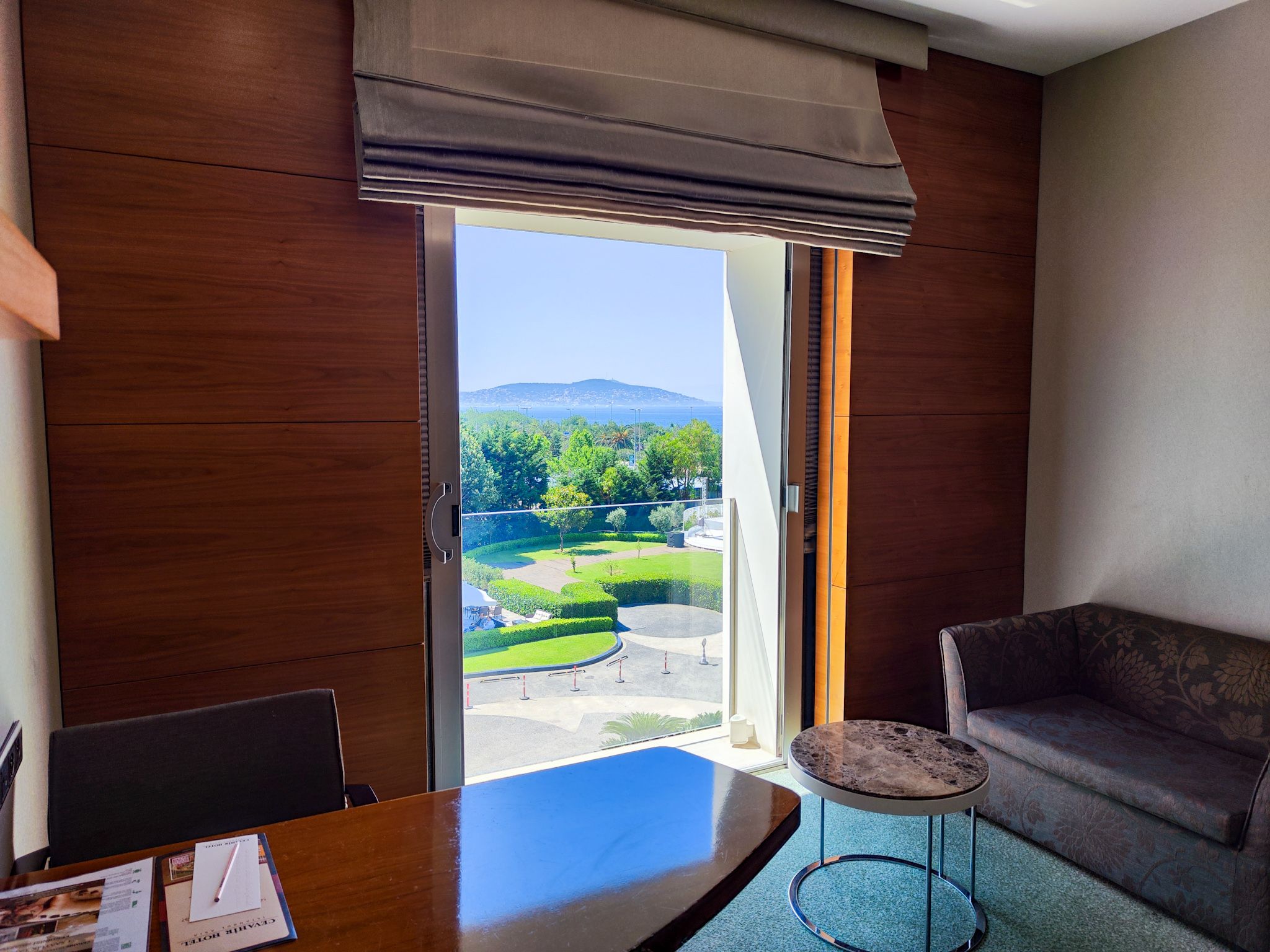 Modern room interior with a desk and sofa, offering a panoramic view of mountains.