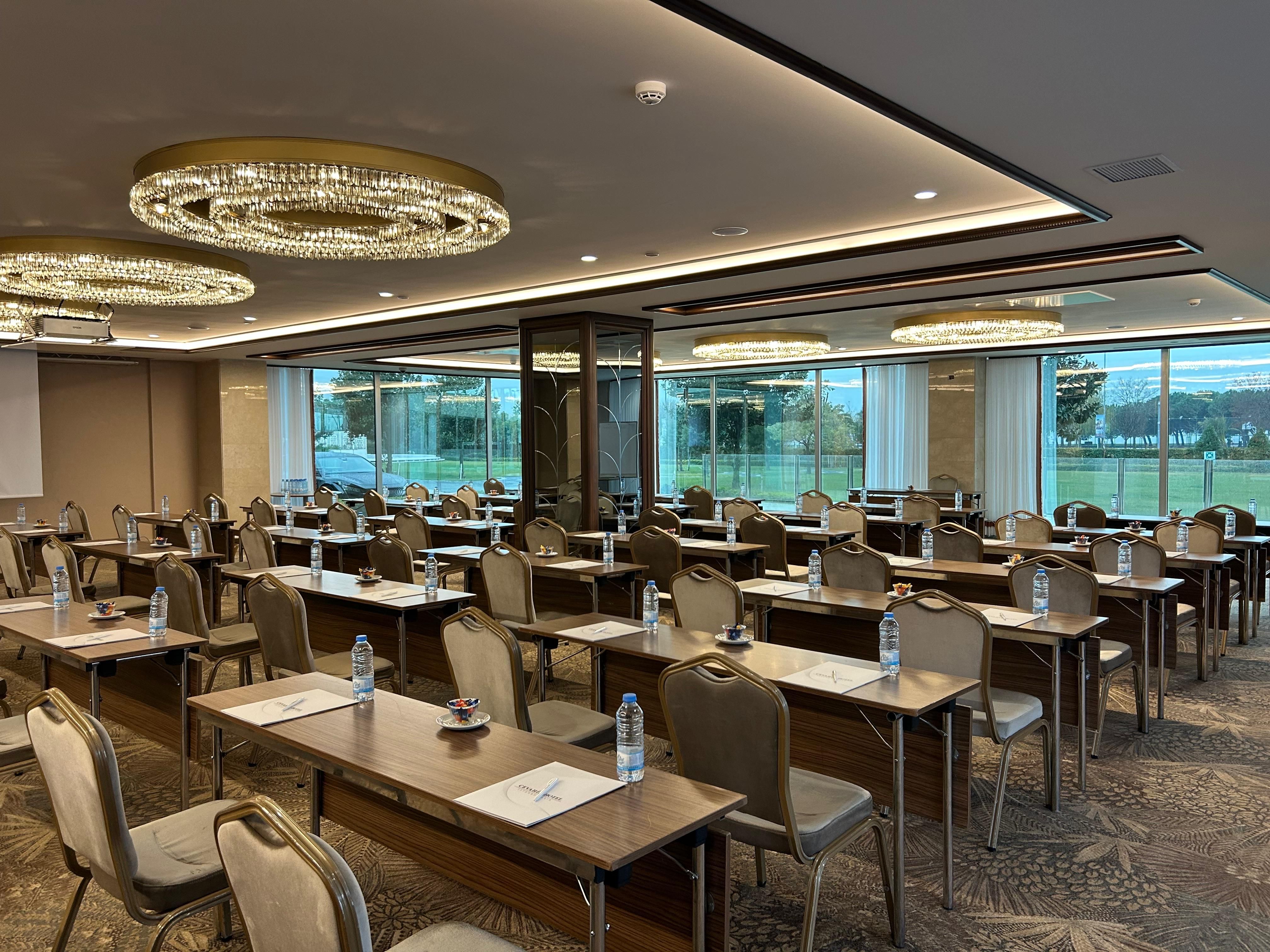 Empty conference room with rows of tables and chairs, set up for a meeting.