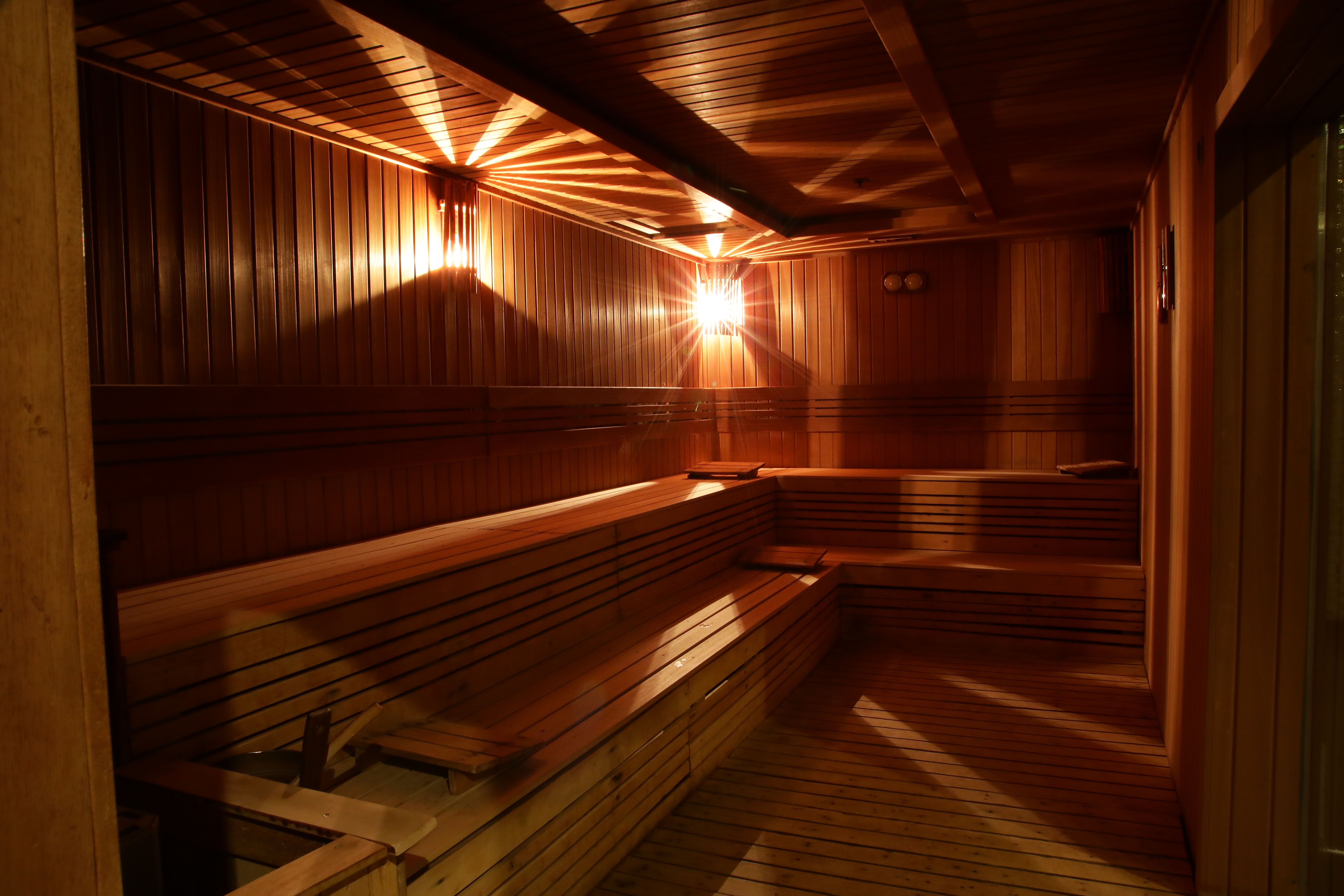 Interior of a wooden sauna with tiered benches illuminated by warm, directional lighting.