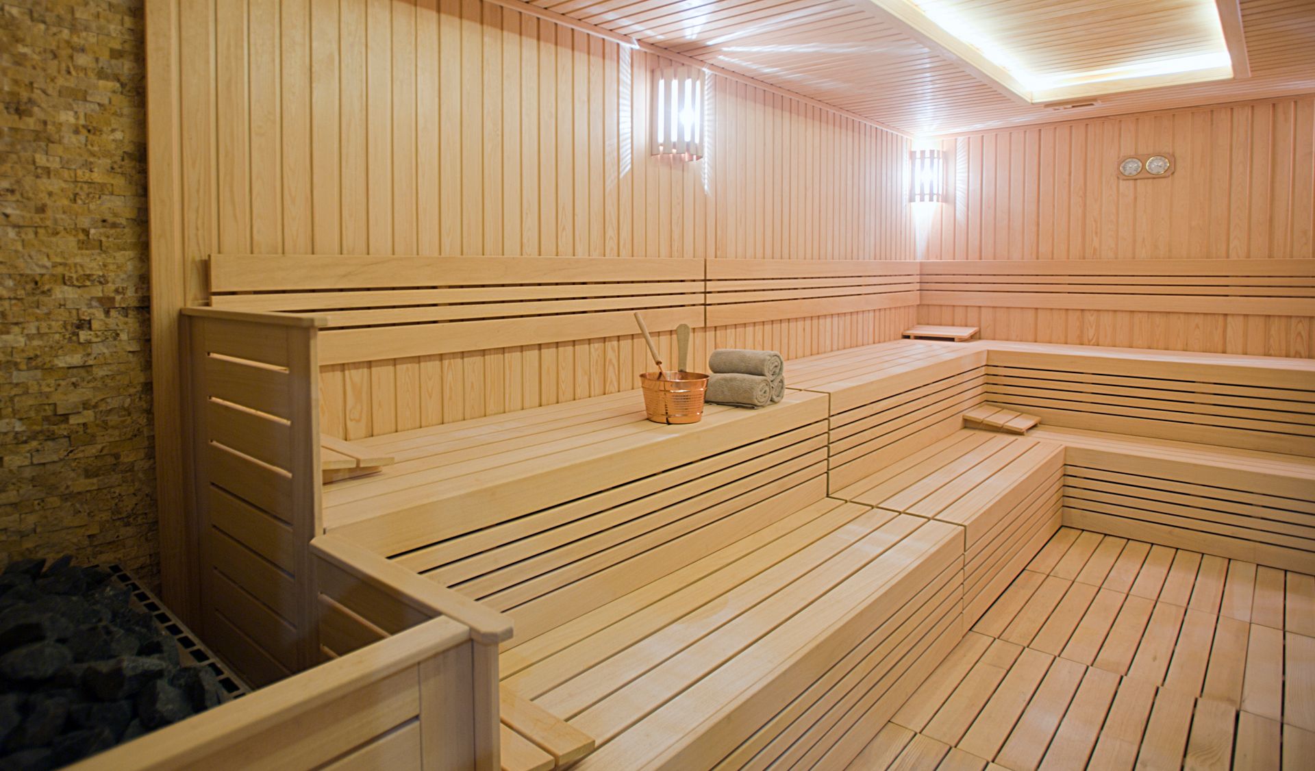 Interior of a traditional wooden sauna with tiered seating and soft lighting.